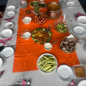 Ein gedeckter Tisch auf orangener Tischdecke mit Suppe, Salat, Dip, Snackgemüse.